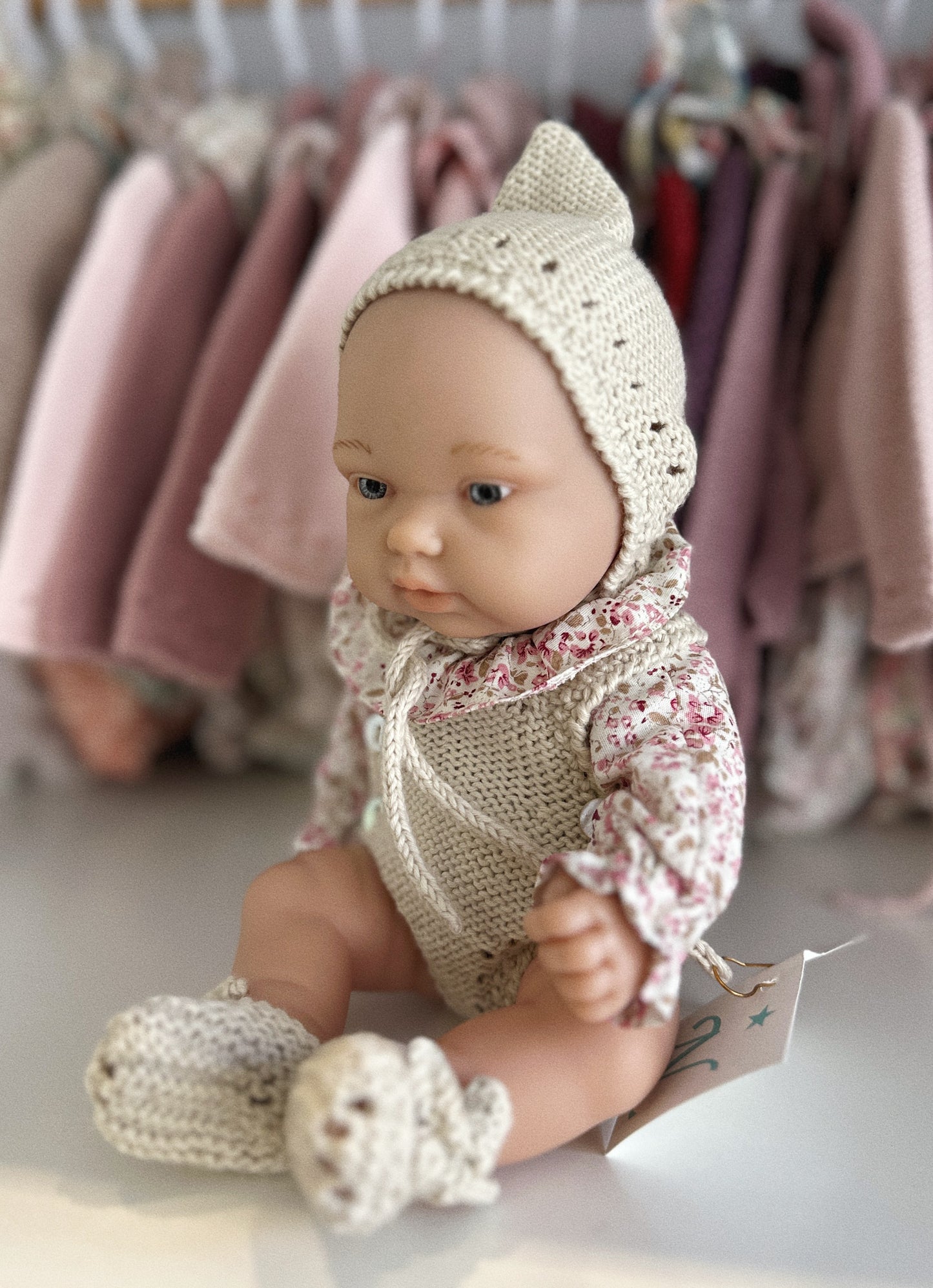 MUÑECA 26CM VESTIDA CON PETO DE PUNTO, CAPOTA DE PUNTO, BLUSA Y PATUCOS
