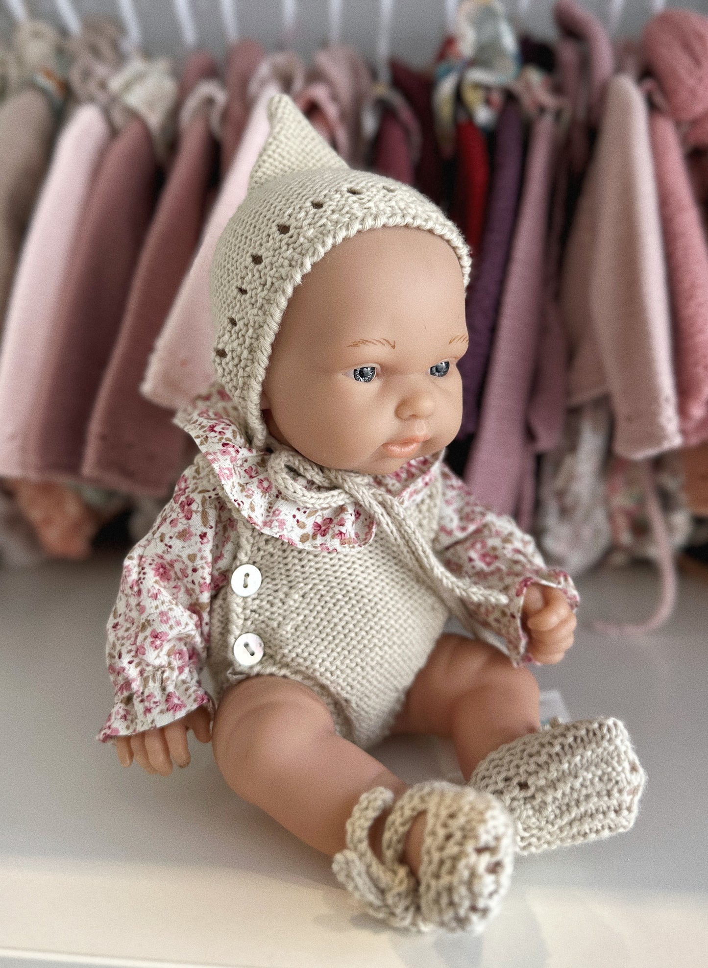 MUÑECA 26CM VESTIDA CON PETO DE PUNTO, CAPOTA DE PUNTO, BLUSA Y PATUCOS