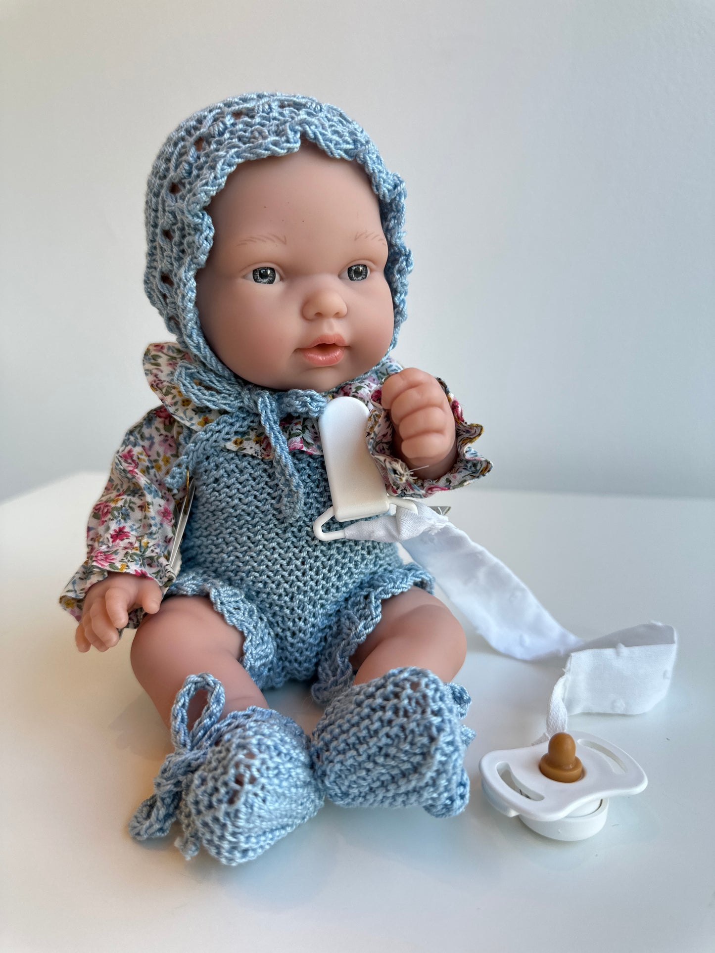 Muñeco 26 centímetros vestido con peto, blusa, capota y patucos